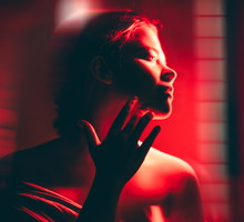 A woman doing full body red light therapy in a dark room