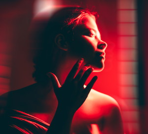 A woman doing full body red light therapy in a dark room