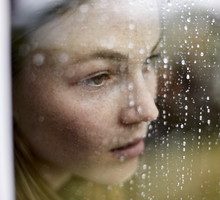 Close-up of pensive young woman looking out of window