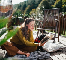 Woman sitting on patio with dog, reading book. Portrait of beautiful woman.
