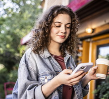 Young woman using smartphone in front of cafe
