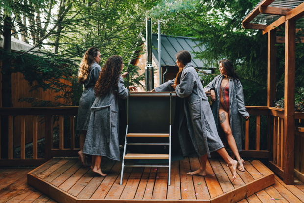 Testing the water before spa. Group of women undresses for hot bath experience in backyard spa