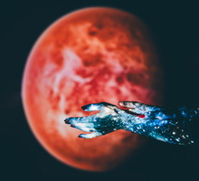 A close-up shot of two hands, projected with a vibrant blue galaxy pattern, are posed against a blurred red planet backdrop.