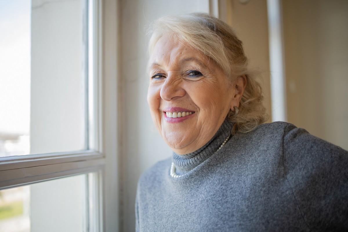 uśmiechnięta seniorka przy oknie