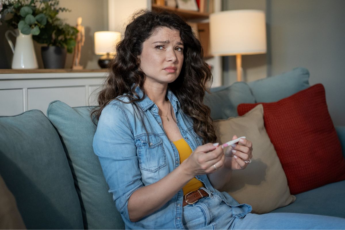 Zmartwiona kobieta z testem ciążowym