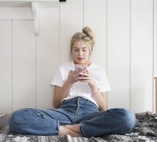 Teen girl with phone sitting on bed