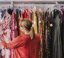 Woman looking at dress hanging on rack while standing at store
