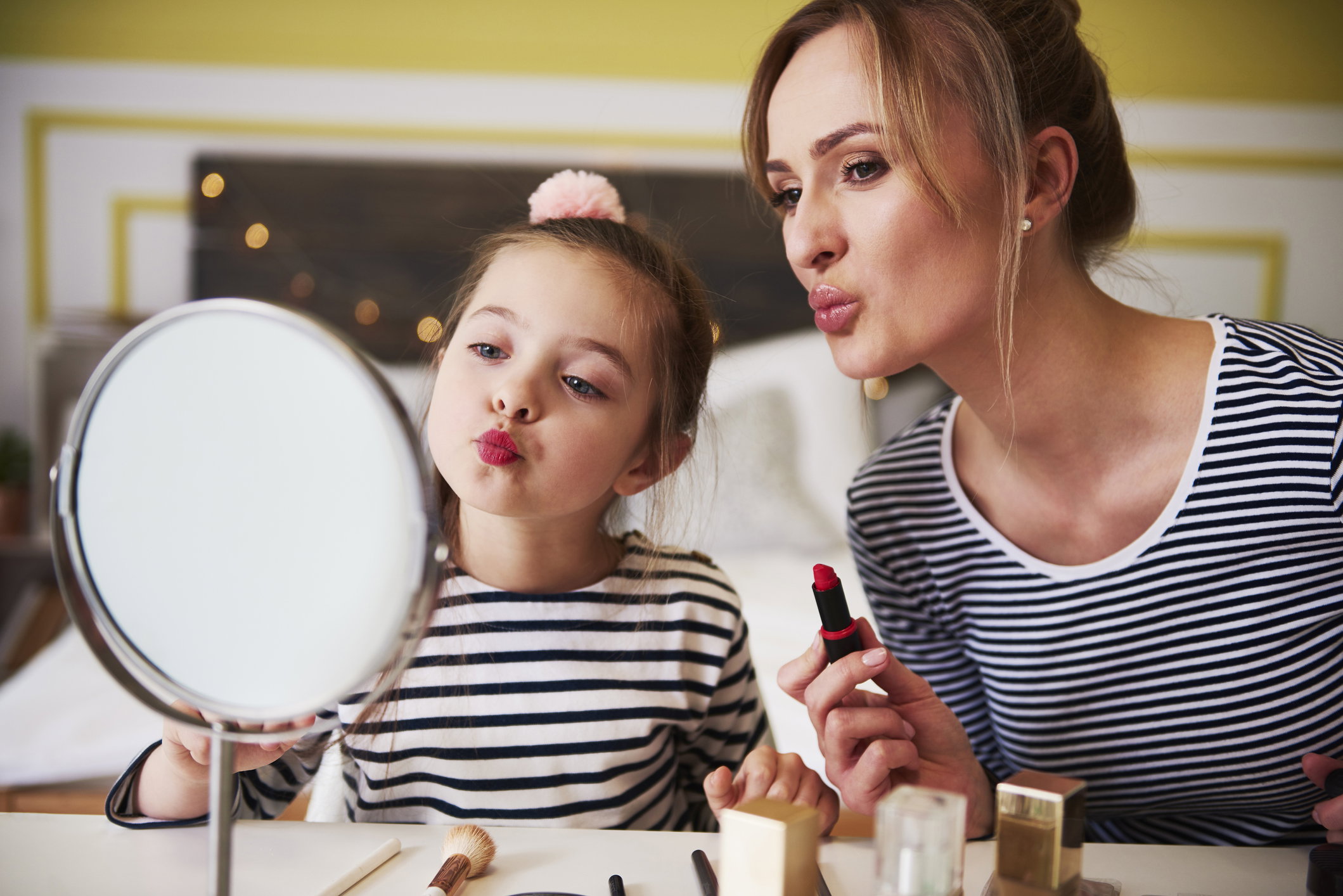 Mother and daughter applying make up together, using lipstick