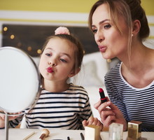 Mother and daughter applying make up together, using lipstick