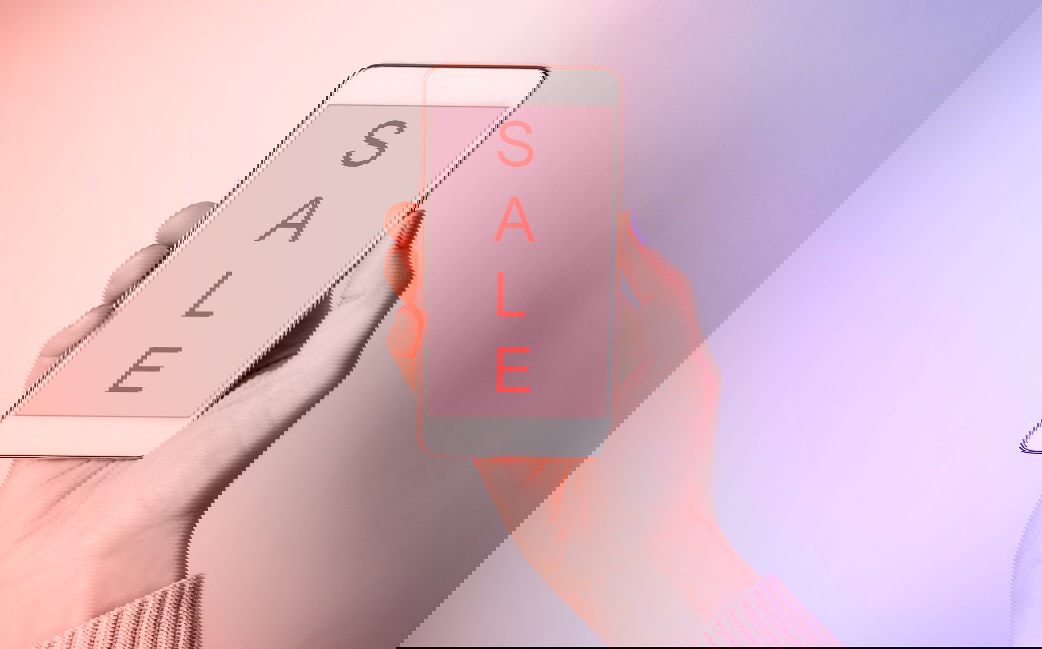 Close-Up Of Woman Hand Holding Mobile Phone Showing Sale Text Against Colored Background