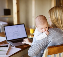 Mother with baby at home using laptop