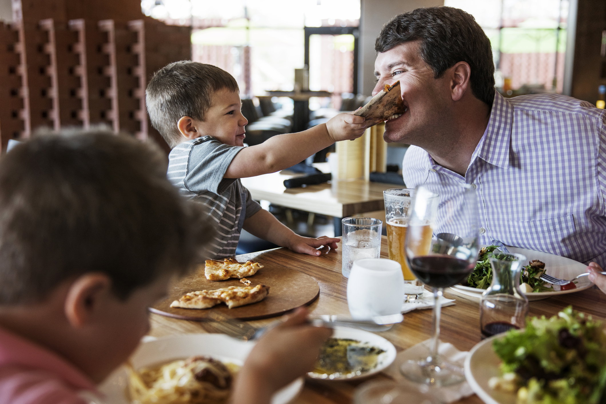 Boy feeding pizza to father in restaurant