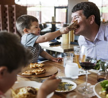 Boy feeding pizza to father in restaurant