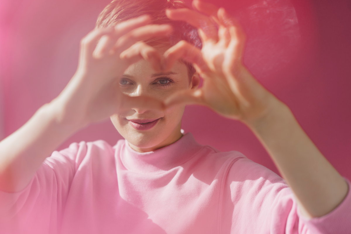 Portrait of woman in pink shaping heart with her hands