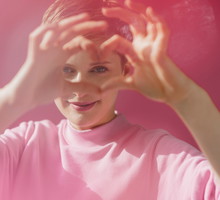 Portrait of woman in pink shaping heart with her hands