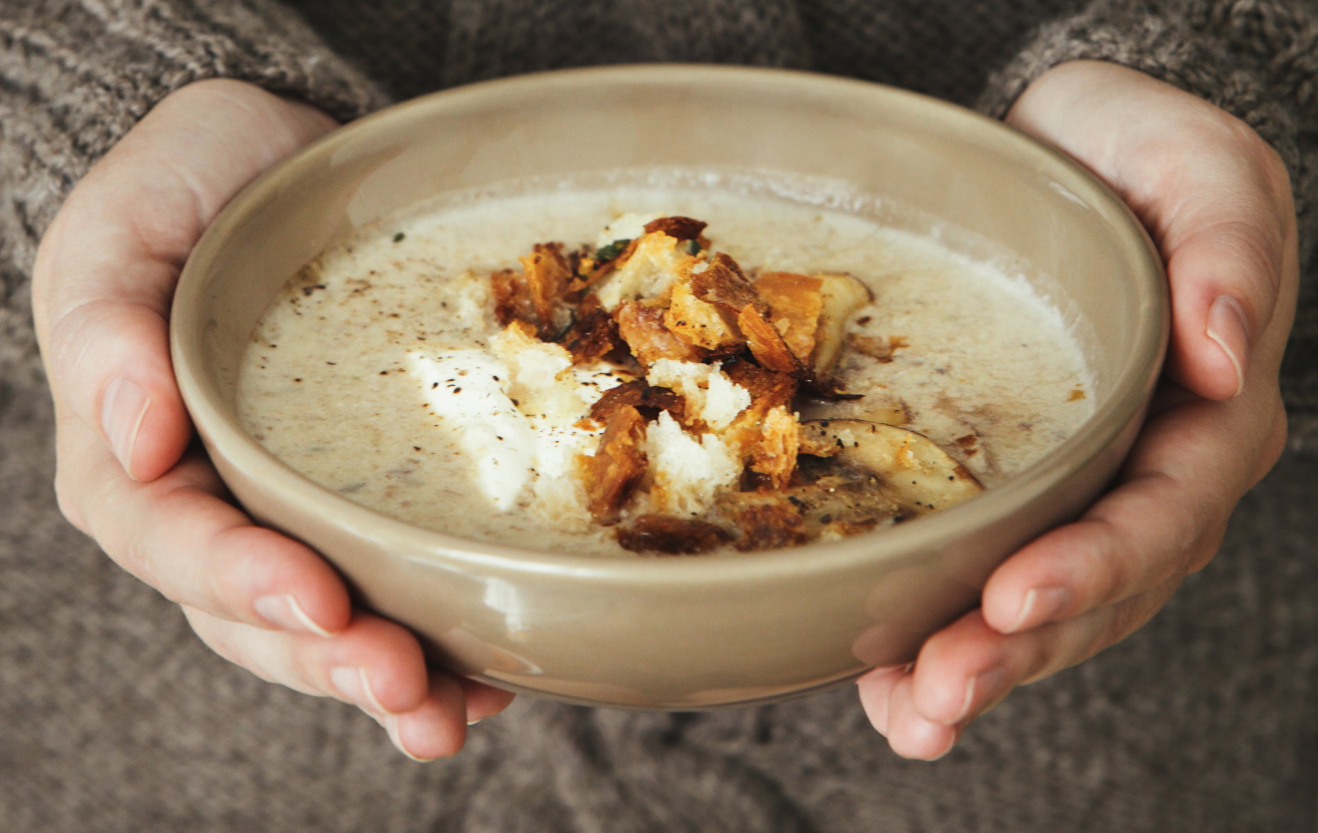 Woman holding bowl with creamy mushroom and white bean soup