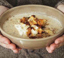 Woman holding bowl with creamy mushroom and white bean soup