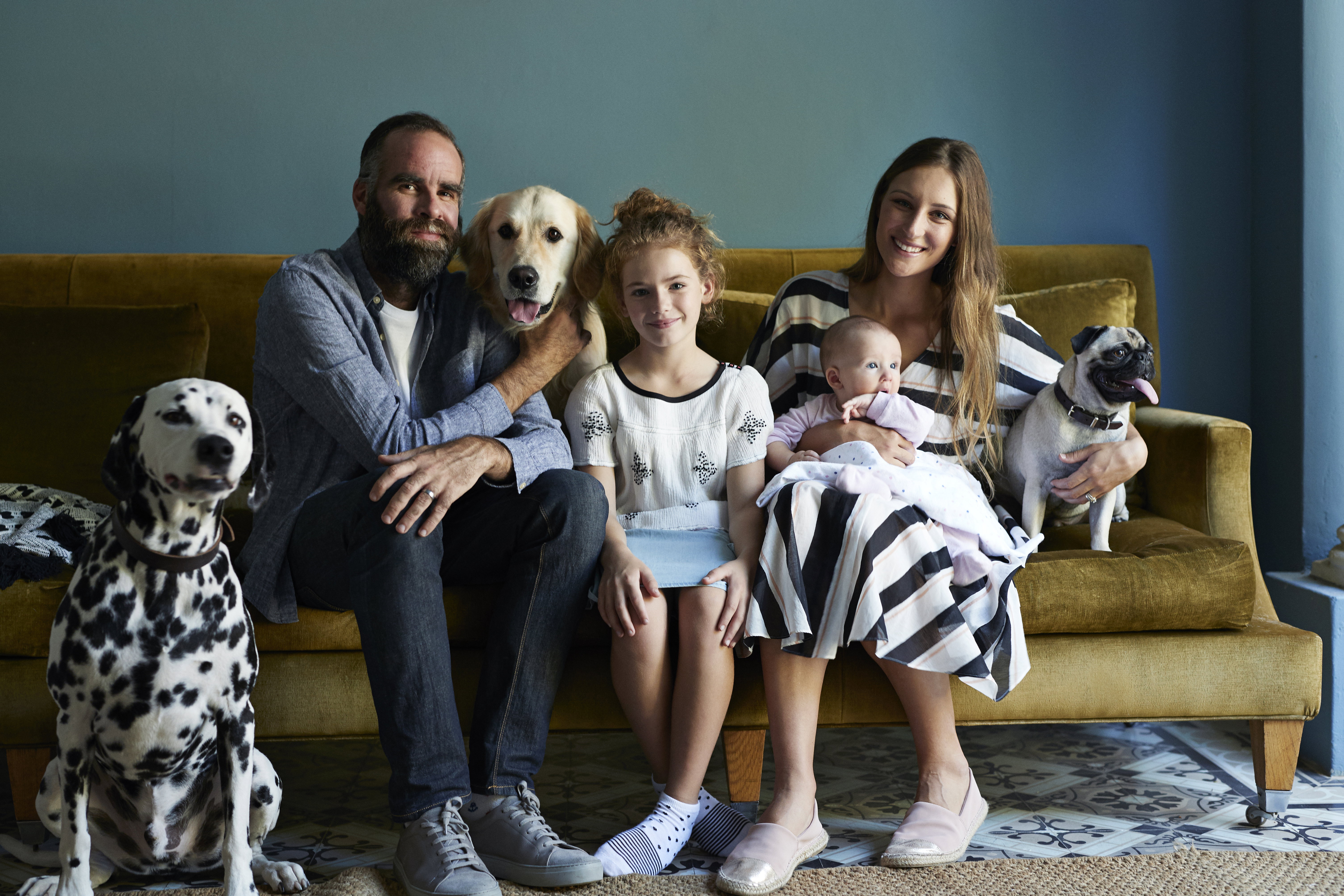 Family sitting together in sofa with their dogs