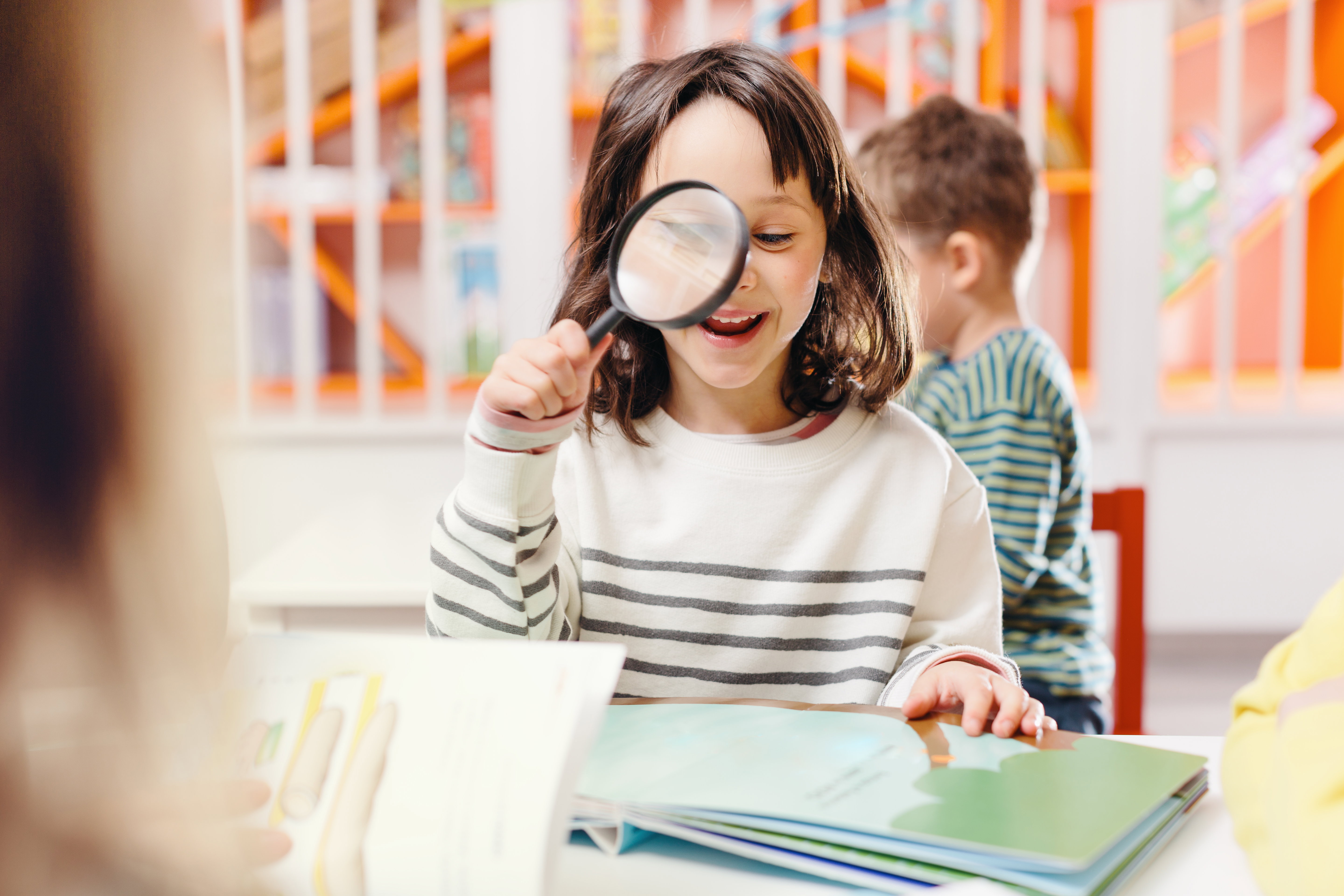 girl smiling reading book with magnifying glass