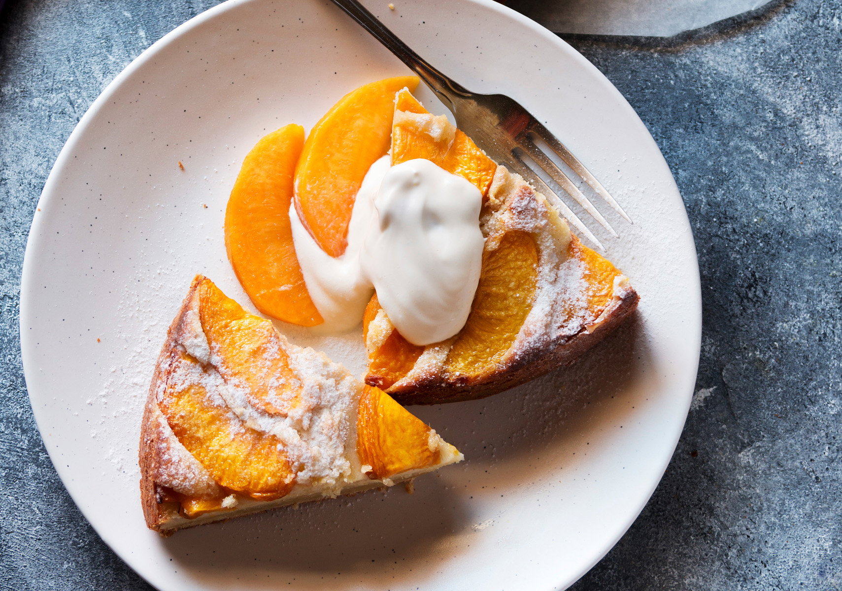 Two slices of peach cake on a plate served with yogurt.Top view