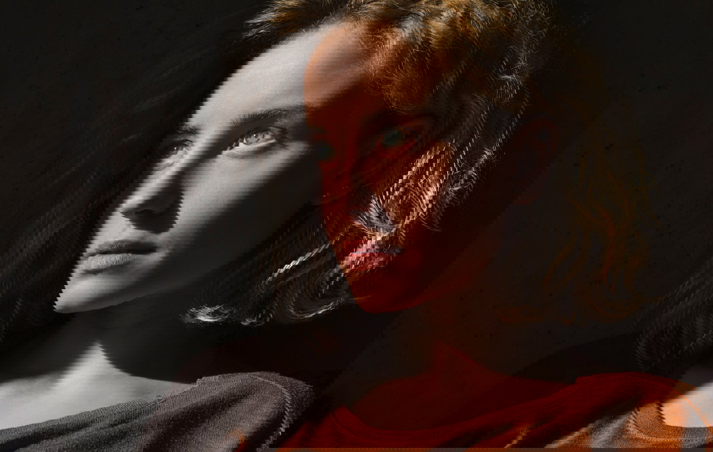 Portrait of pensive student with book looking at distance