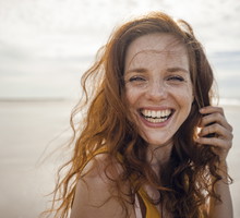 Portrait of a redheaded woman, laughing happily on the beach