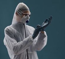 A medical professional in an antiplague suit is fully protected from the virus and wear sterile rubber gloves.
