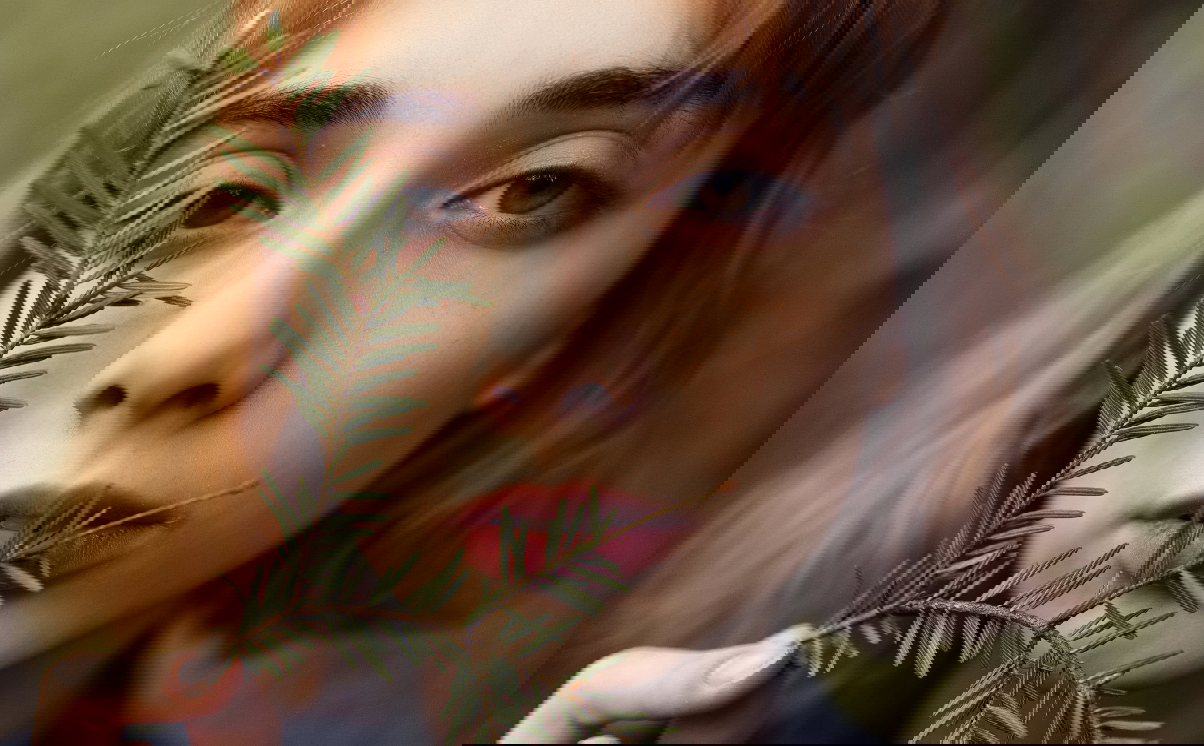 Young woman looking at camera behind twig