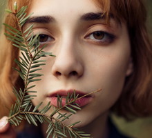 Young woman looking at camera behind twig