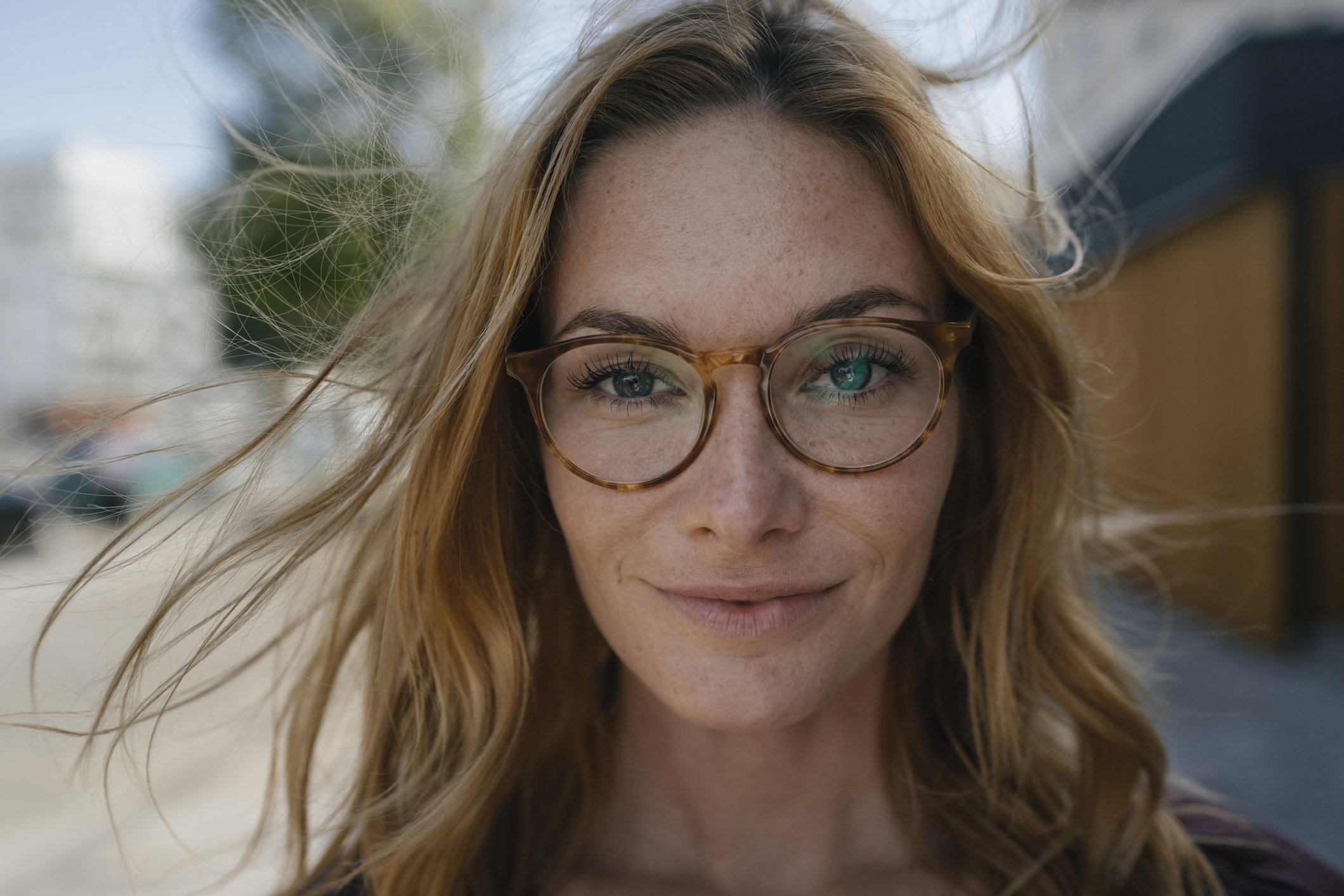 Portrait of confident young woman with glasses and windswept hair