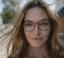Portrait of confident young woman with glasses and windswept hair