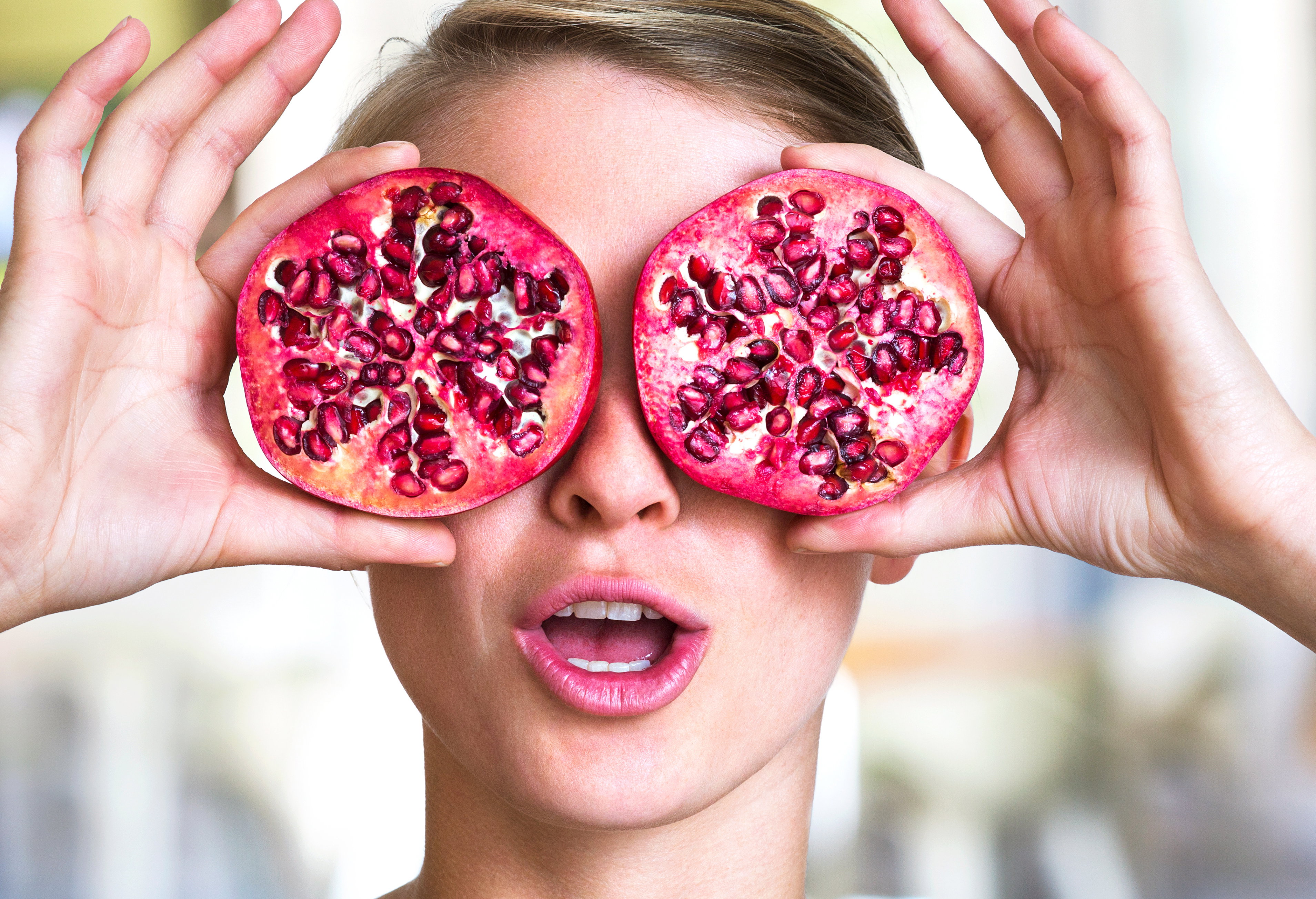 Young woman holding pomegranate slices as glasses