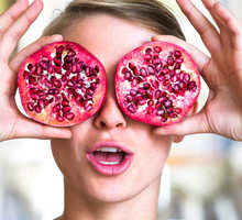 Young woman holding pomegranate slices as glasses