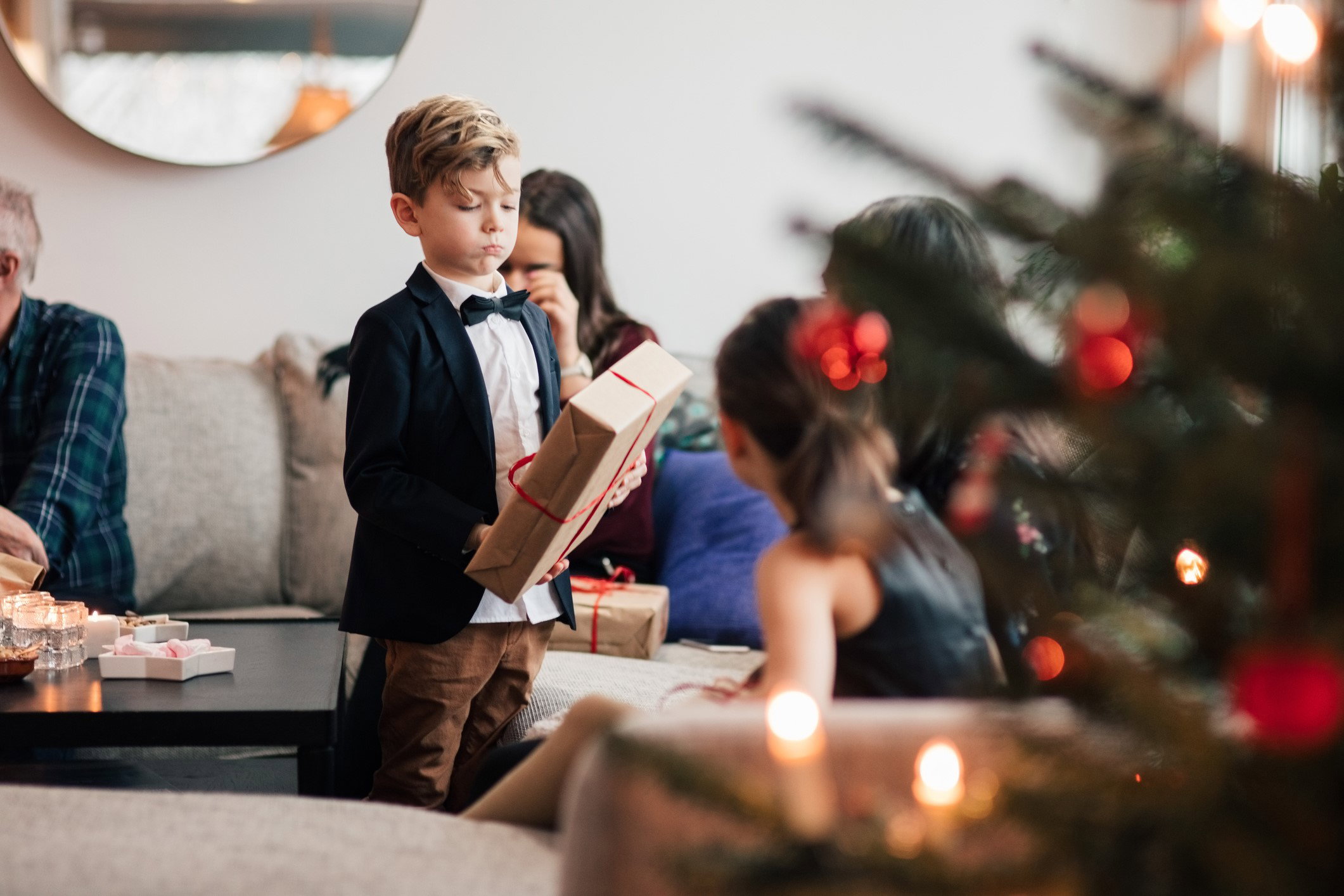 Boy with family looking at Christmas presents in living room