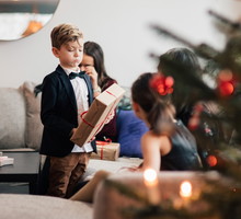 Boy with family looking at Christmas presents in living room