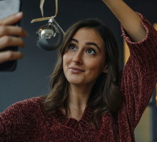 Smiling young woman taking a selfie at Christmas tree