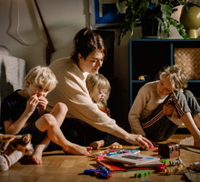 Mother playing with children while sitting on floor at home