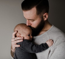 Young man kissing baby son on head, head and shoulders