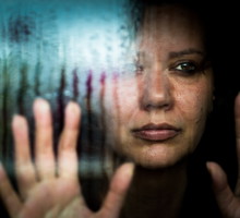 Depressed woman looking out of rainy window
