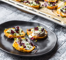 Slices of sweet potato with cream cheese, ramson cream, goat cheese, cress and cranberries