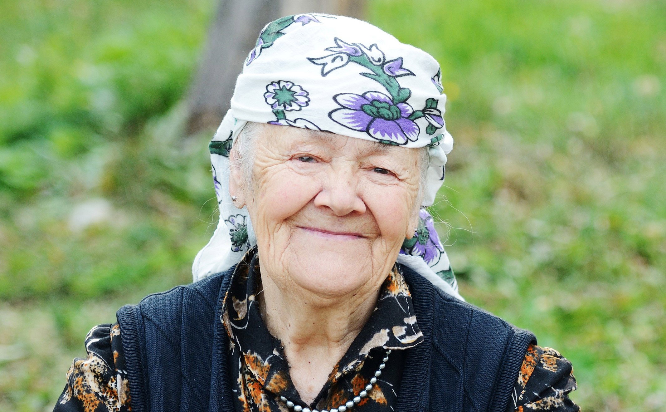 Very aged woman sitting in nature, portrait