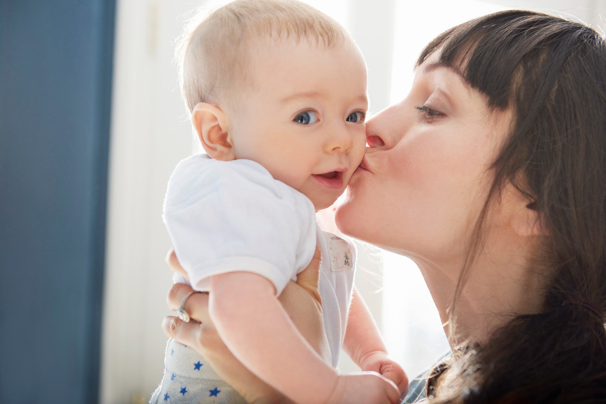 Mother kissing smiling baby