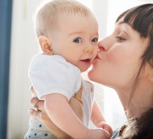 Mother kissing smiling baby