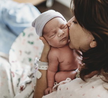 Close up detail of mother kissing newborn son's cheek in hospital