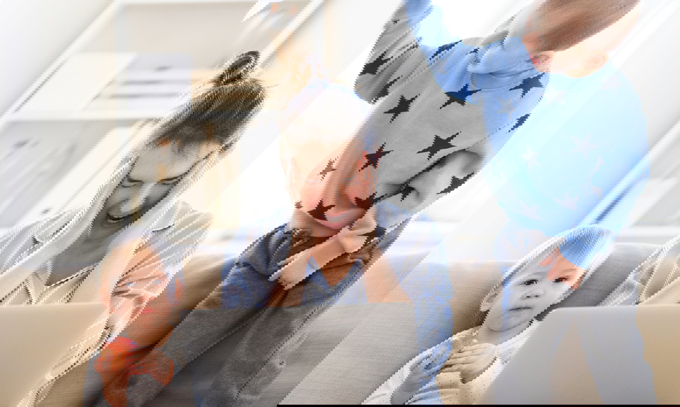 Stressed and frustrated mother with two small children in pajams working in home office, quarantine concept.