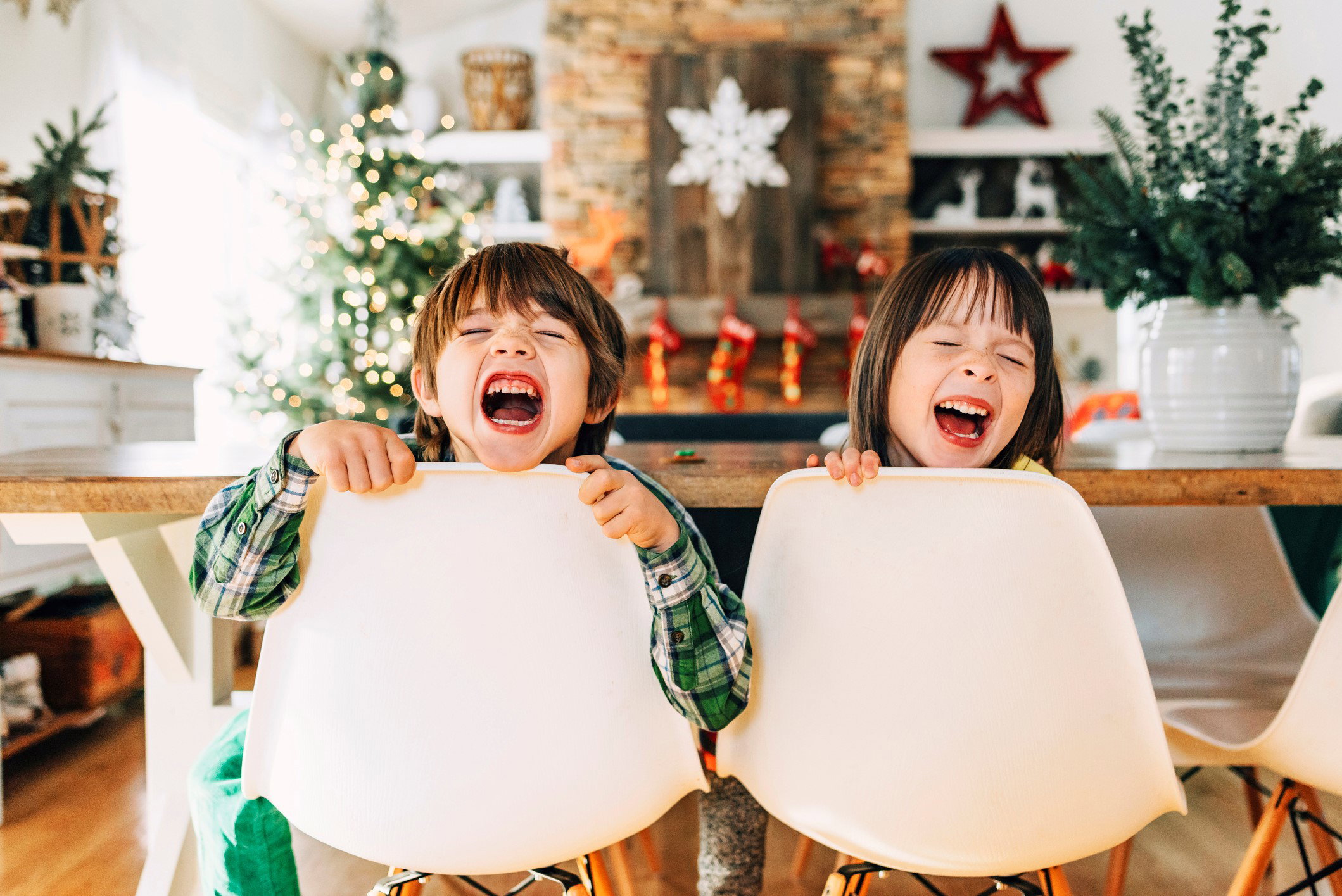 Boy and girl sitting at the dining table messing about at Christmas