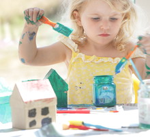 Young girl painting small cardboard houses