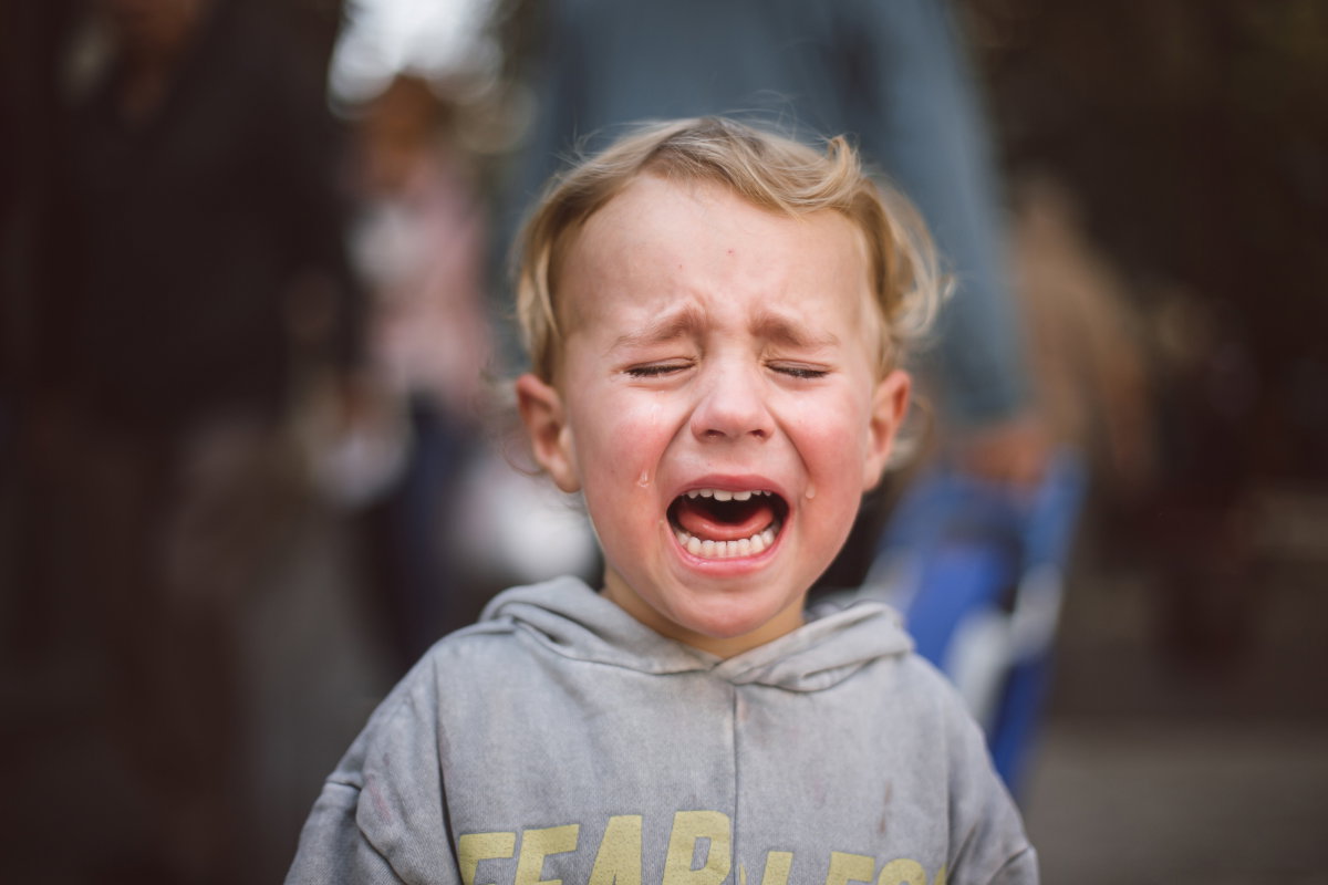 Close-up of a crying boy in the street