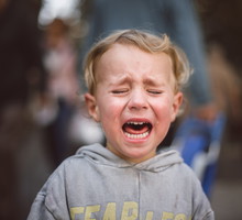 Close-up of a crying boy in the street