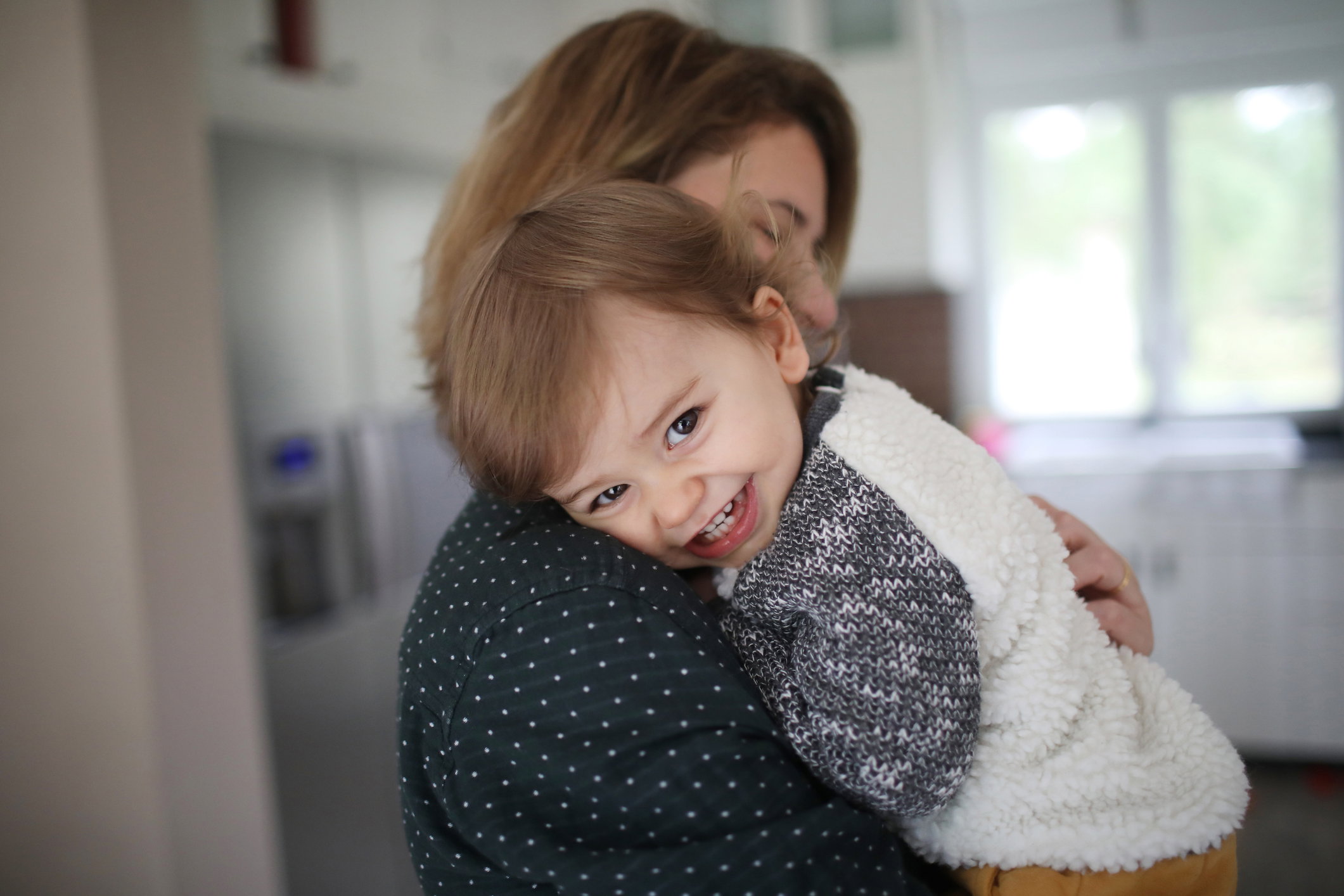 A mum hugging her 1 year old baby boy in the kitchen